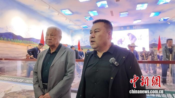 柯柯牙三北防护林管理站首任站长依马木·麦麦提(左)与其儿子艾斯卡尔·依马木(右)接受采访。 中新网记者 姜雨薇 摄