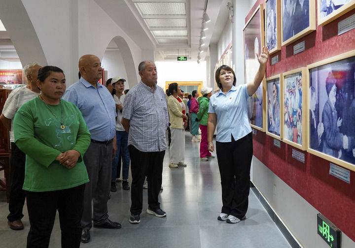 在新疆和田地区于田县库尔班&middot;吐鲁木纪念馆，如克亚木&middot;麦提赛地（右一）向参观者介绍展出的照片（2025年9月14日摄）。新华社记者 丁磊 摄