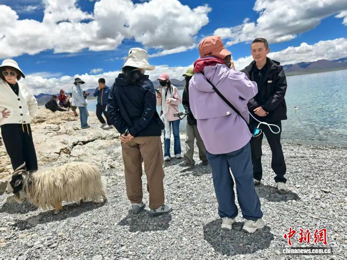 7月16日，“辉煌60载 魅力新西藏”集中采访活动中，张龙泉(右一)在纳木措湖畔介绍景区发展情况。中新社记者 程小路 摄