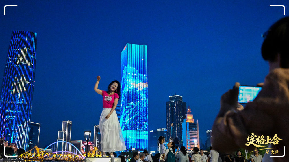 游客在天津市的海河岸边拍照打卡。