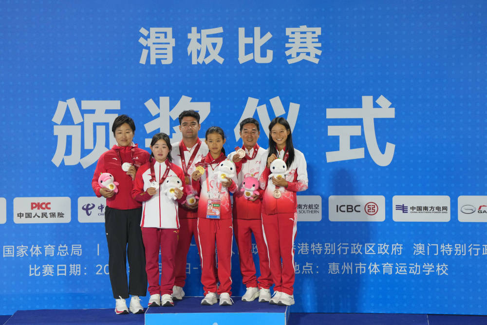 11月11日,第十五届全国运动会滑板项目女子碗池赛决赛在广东惠州举行。冠军广东队选手邹明珂(右三)、亚军山东队选手孟令妍(左二)、季军广东队选手郑好好(右一)和教练在颁奖仪式上合影。新华社记者 刘坤 摄