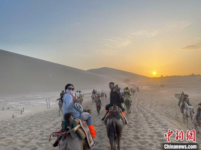 图为台胞青年在鸣沙山月牙泉景区体验骑骆驼　申志波　摄