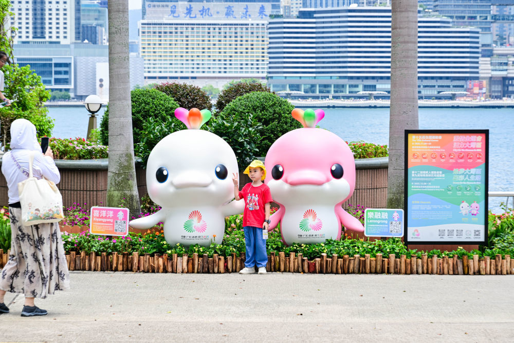 8月1日,一名儿童在香港金紫荆广场的第十五届全国运动会吉祥物旁留影。新华社记者 朱炜 摄
