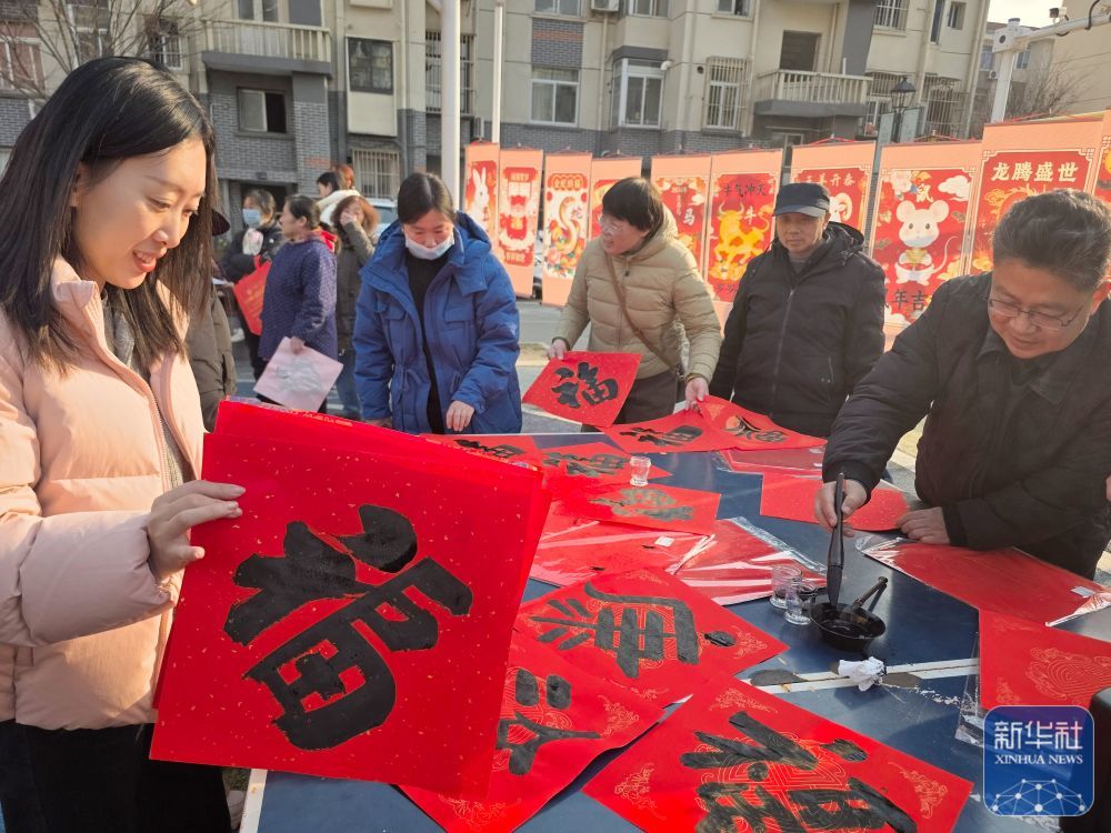↑1月23日，江苏省南通市崇川区新城桥街道社区居民在新春公益集市现场领取福字。新华社发（许丛军摄）