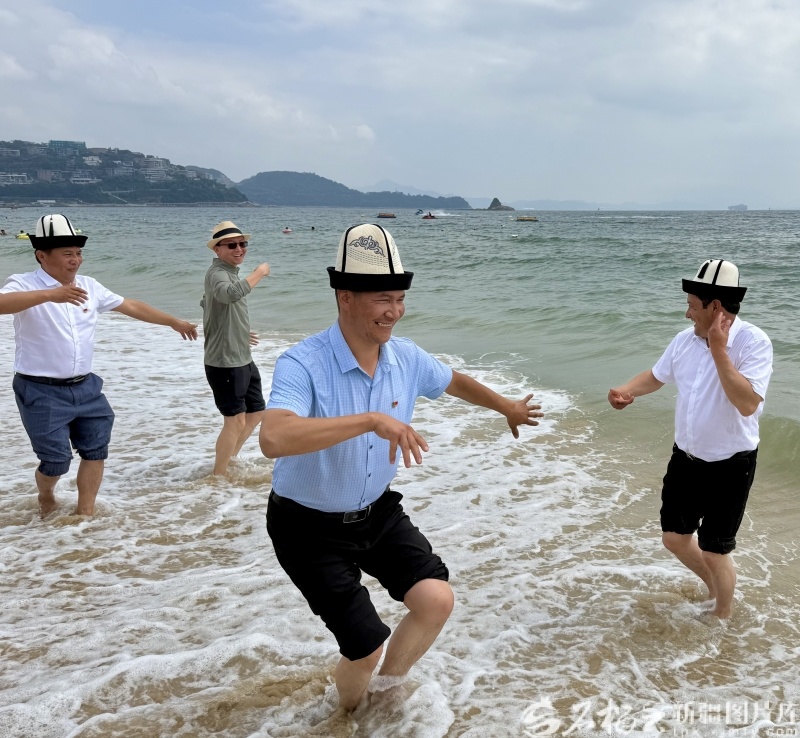10月16日,深圳市盐田区大梅沙海滨公园,昆仑山牧民和深圳摩友在沙滩上欢快地跳起新疆舞(从左到右依次为:麦麦提萨伍提·亚森、余传仁、阿卜杜热伊木·阿散、阿伍提·亚森)。石榴云/新疆日报记者 郭倩摄