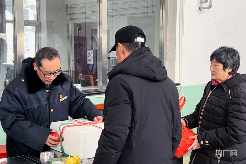 蓟州北站客运员陈宝泉为进站旅客捆扎零散年货包装盒（央广网发 肖亦杰 摄）