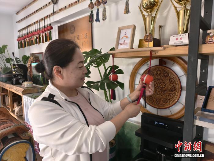 社区居民侯艳霞是非遗皮雕工作室的常客，她给记者展示制作的“小石榴”挂件。中新网记者 勉征 摄