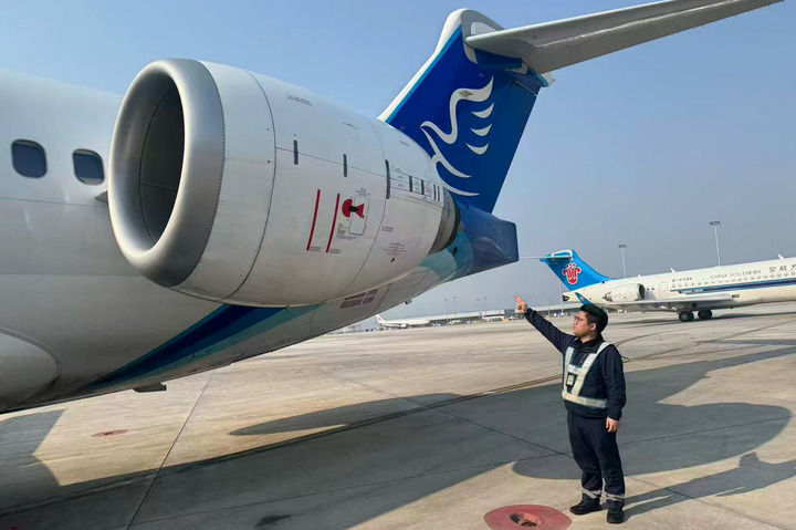 2月21日,在重庆江北国际机场,华夏航空维修技术员黄伦辉在国产支线客机C909旁工作。新华社发