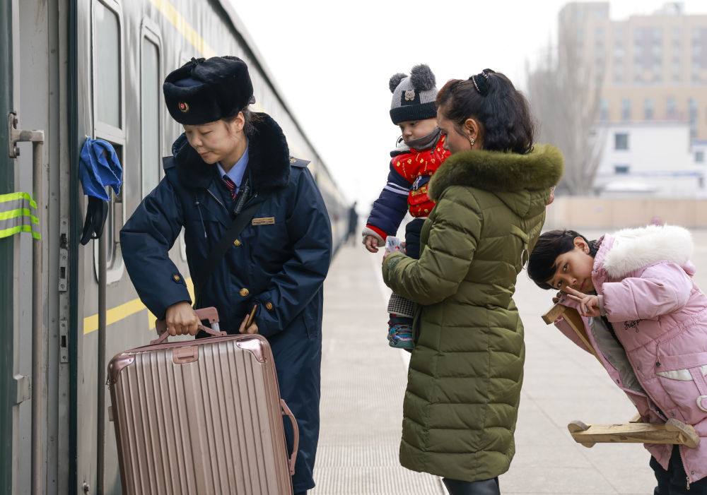 在喀什站站台，列车工作人员帮旅客将行李搬上7557次列车（2025年1月2日摄）。新华社记者 王菲 摄