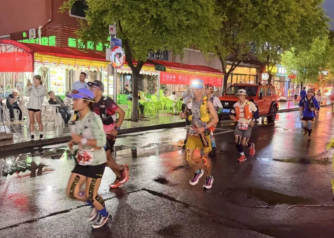 （选手夜间带着头灯跑过城市中的美食街）