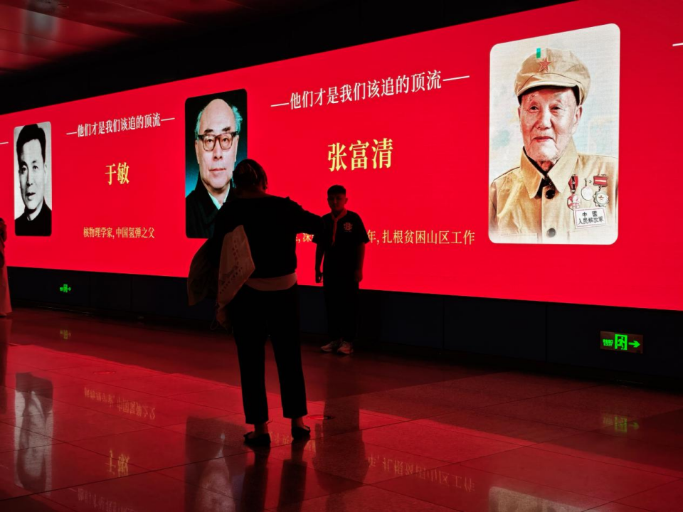 10月1日,在郑州地铁会展中心站,一位小朋友正站在科学家海报前拍照。新华社记者 刘振坤 摄