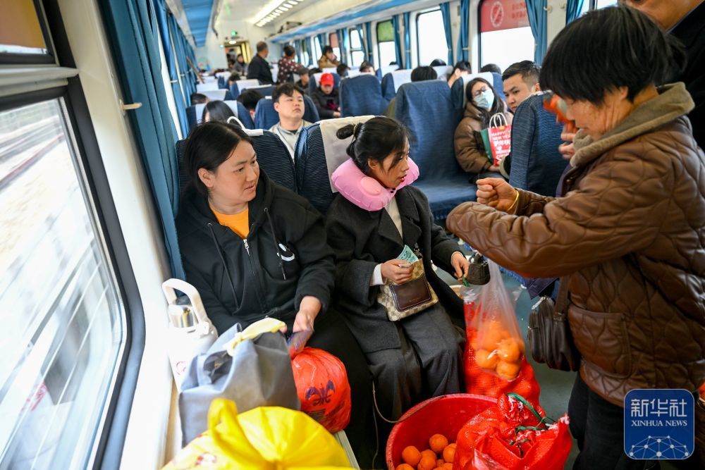 ↑ 2月12日,在7272次列车车厢内,来自湖南的村民(右)和乘客进行交易。新华社记者 刘续 摄