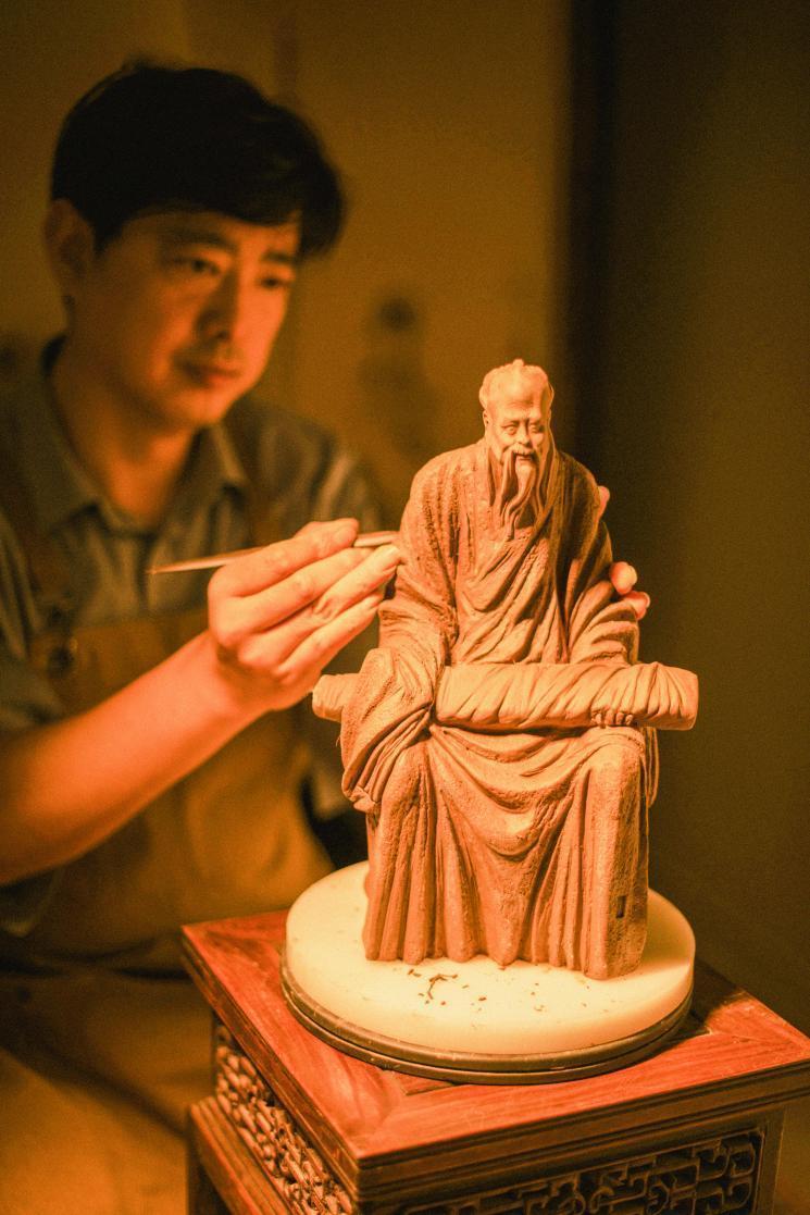 张宇在制作泥塑作品《孔子抚琴》