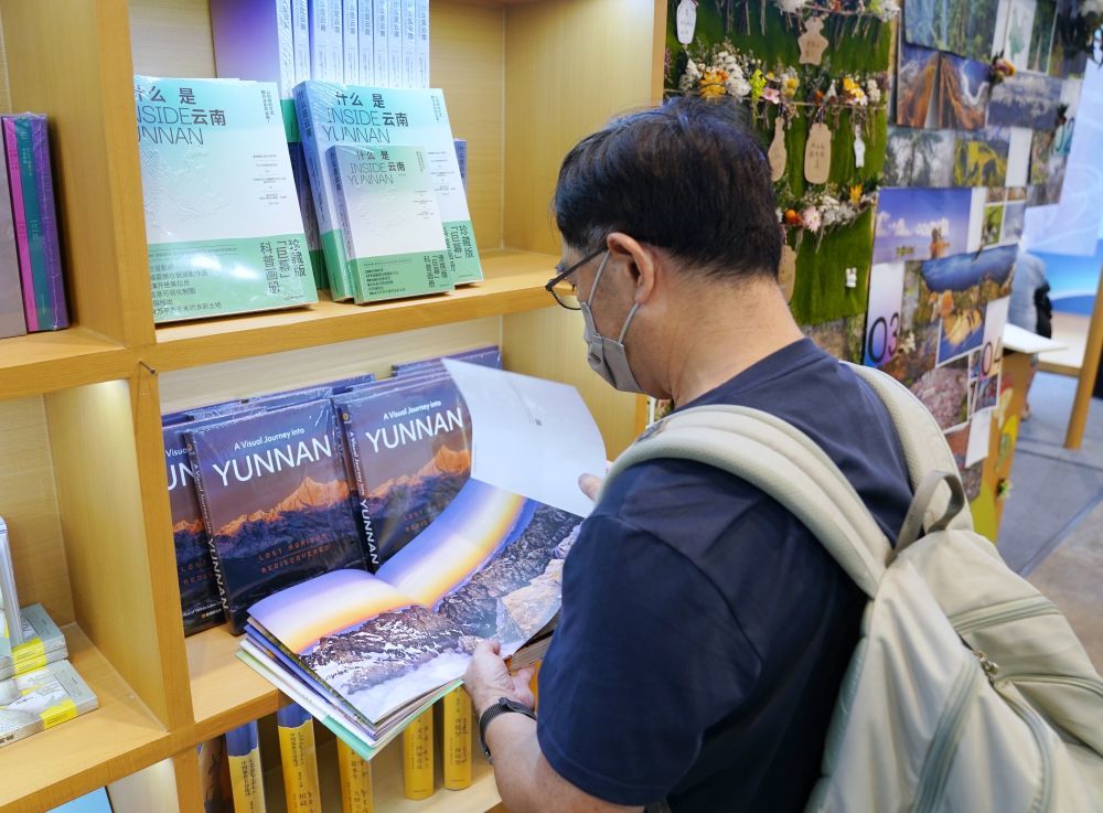 7月15日，在香港会展中心，读者在内地展区主题省云南展区观看画册。（配本社同题文字稿）新华社发（王申摄）