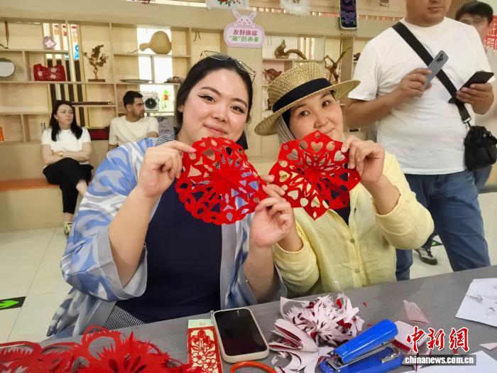 图为中亚主流媒体采访团成员在精河县锦福社区体验剪纸技艺。赵凯 摄