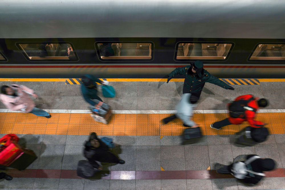 2月2日，在北京西站，乘坐G6701次列车的旅客在站台工作人员引导下排队乘车。新华社记者 鞠焕宗 摄