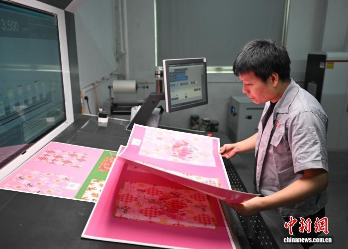 5月26日,义乌一家圣诞用品生产企业内,工人查看自动化设备制作的圣诞礼品袋材料。 王刚 摄