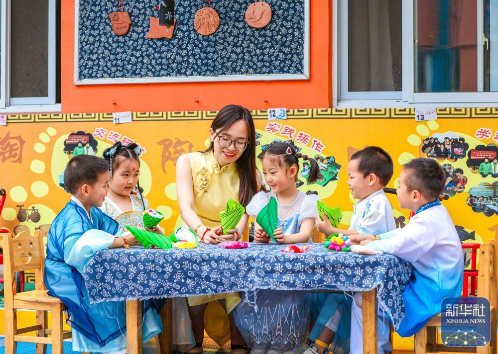 ↑ 6月17日,在江苏省扬州市江都区育才幼儿园,老师带领小朋友制作粽子模型。新华社发(任飞摄)