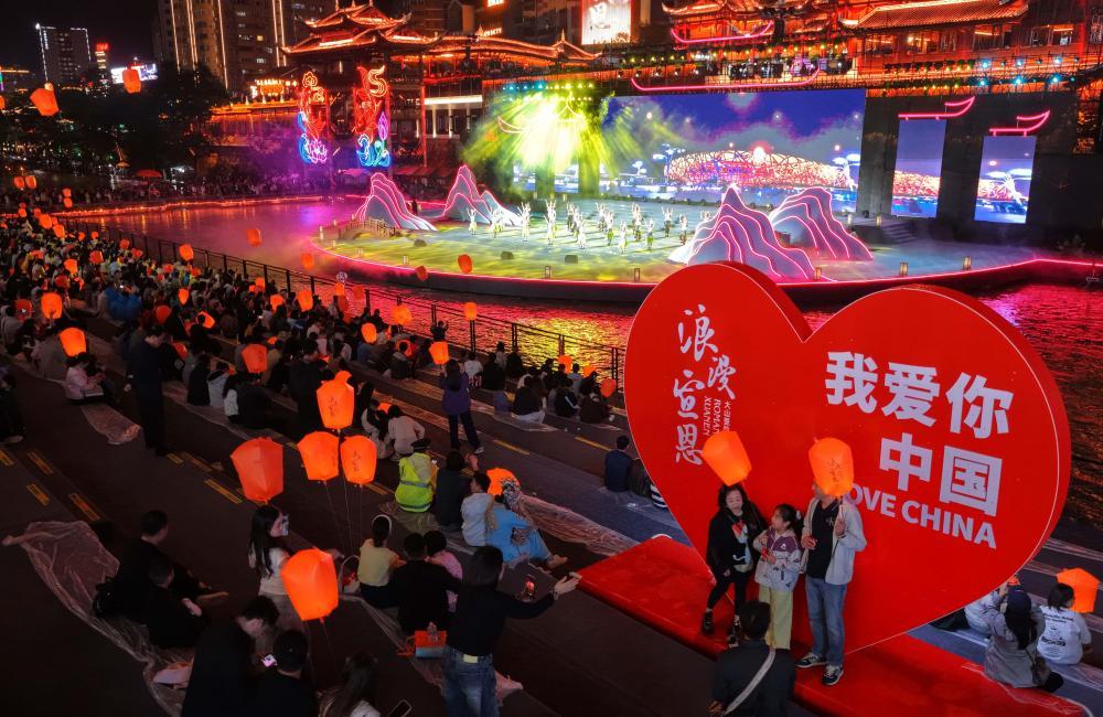 10月3日晚,游客在湖北省宣恩县城贡水河畔观看歌舞展演(无人机照片)。 新华社发(宋文摄)