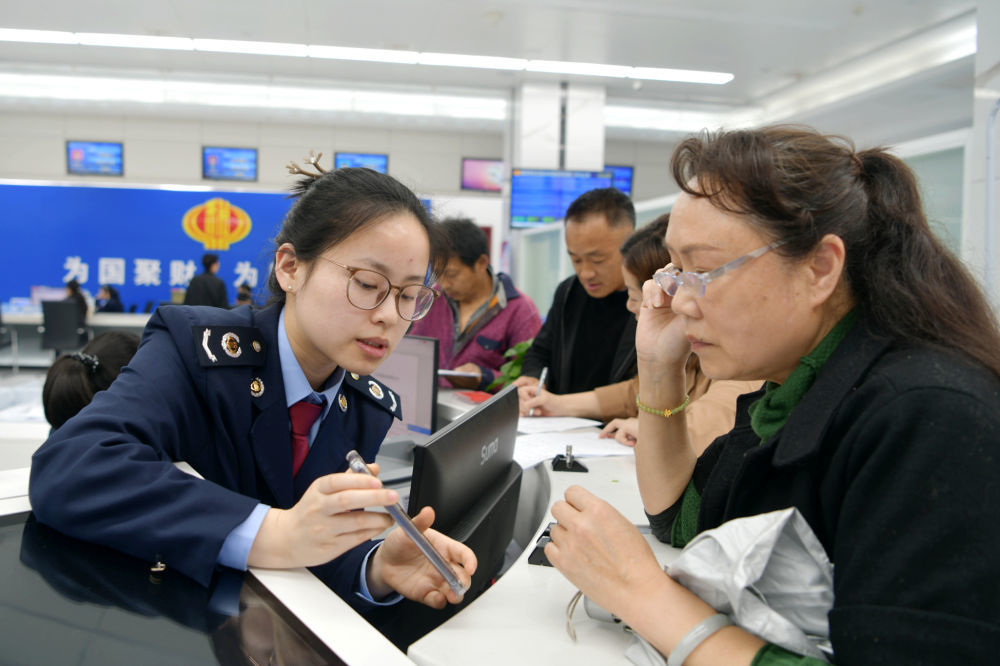 4月8日，在湖北省咸宁市通城县政务服务中心，工作人员指导市民手机办理纳税业务。新华社发（刘建平 摄）