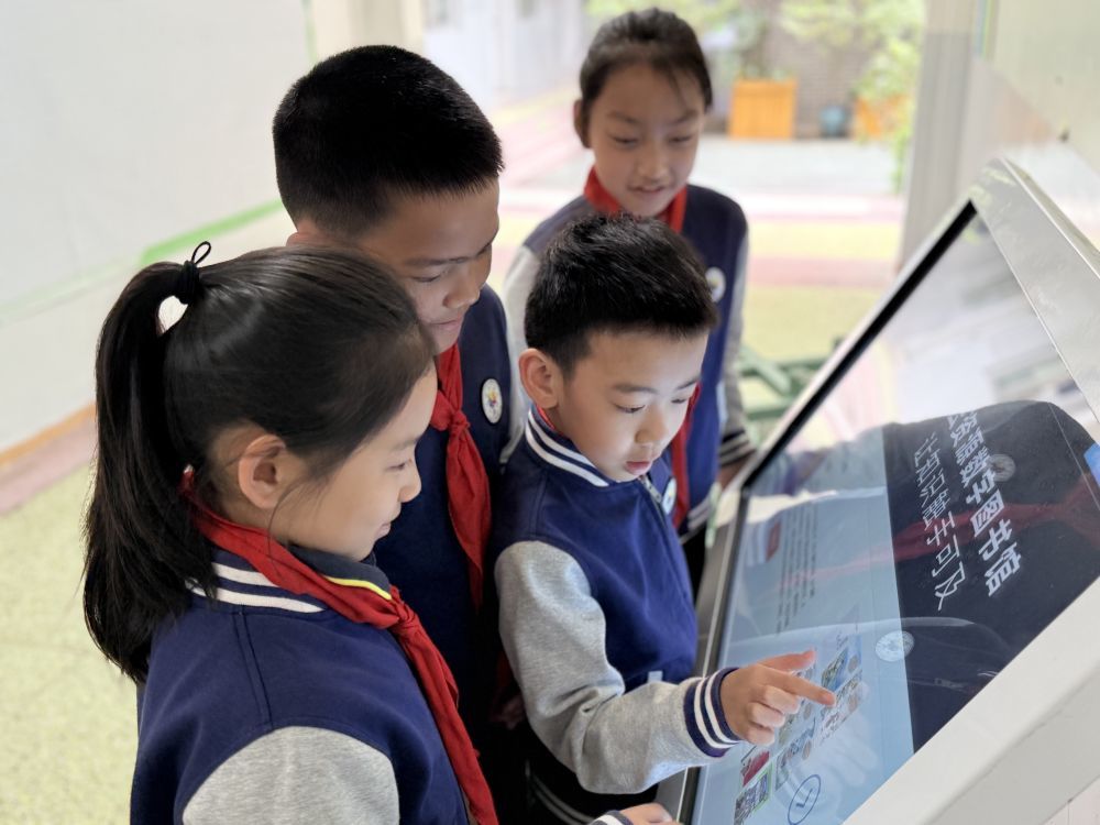 四川省成都师范附属小学部分学生课间在教学楼一楼的电子阅读机旁选书阅读。（成都师范附属小学供图）