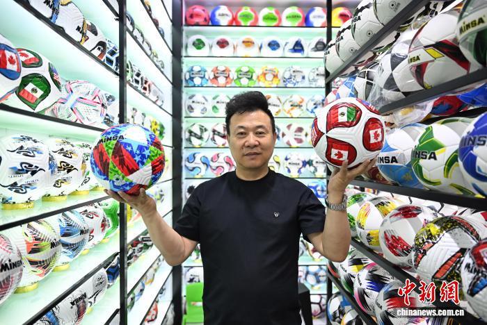 6月4日，义乌商户陈绍美展示世界杯纪念足球。近日，随着美加墨世界杯临近，中国“小商品之都”浙江义乌不少企业加紧生产和供应世界杯周边产品，积极满足持续增长的市场订单需求。　中新社记者 王刚 摄