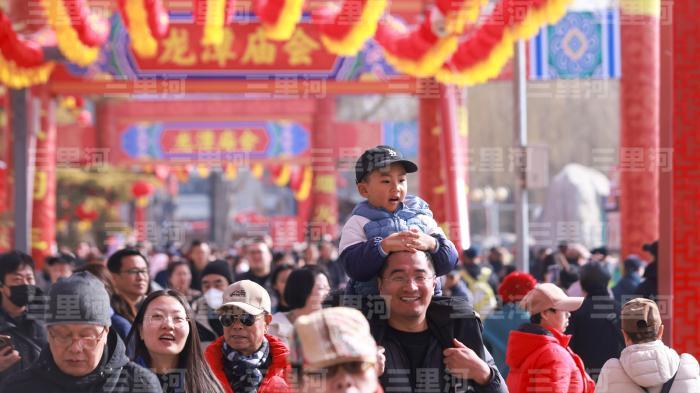2月20日，北京，第四十届龙潭春节文化庙会年味十足。游客在庙会品小吃、赏民俗、度过春节假期。图为家长带着小朋友逛庙会。中新社记者 贾天勇 摄