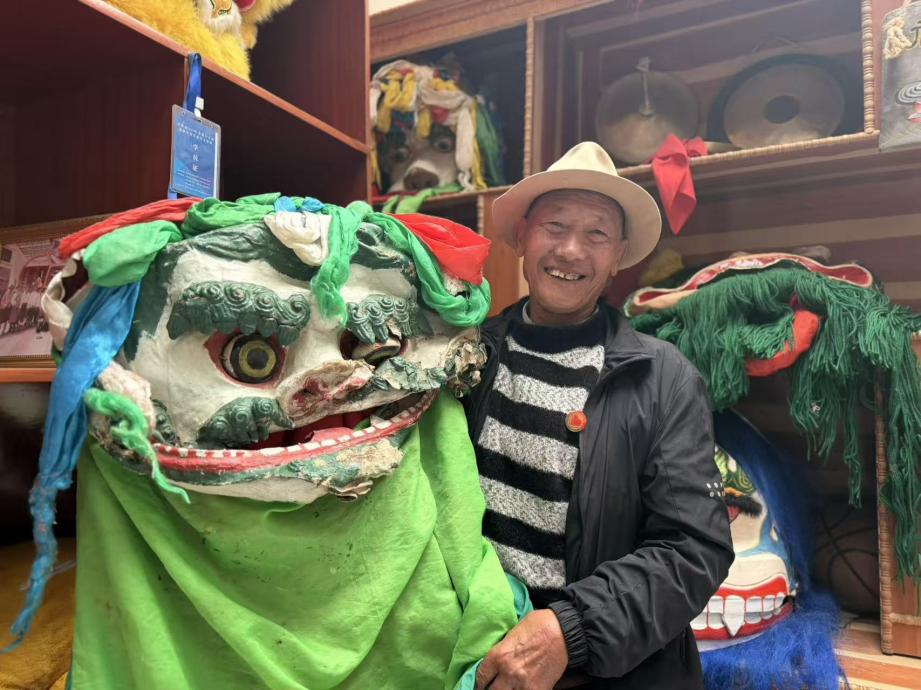 图为硕督狮子舞第五代传承人邓巴阿尼与家族代代珍藏的古老狮头合影。罗雨欣摄