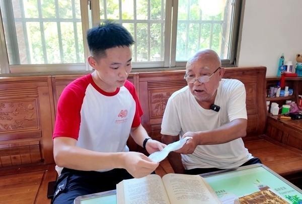 广西壮族自治区全州县才湾镇才湾村村民、米花山红军烈士墓守墓人蒋石林(右一)向北京城市学院学生讲述家族守墓的故事。皇甫俊杰供图