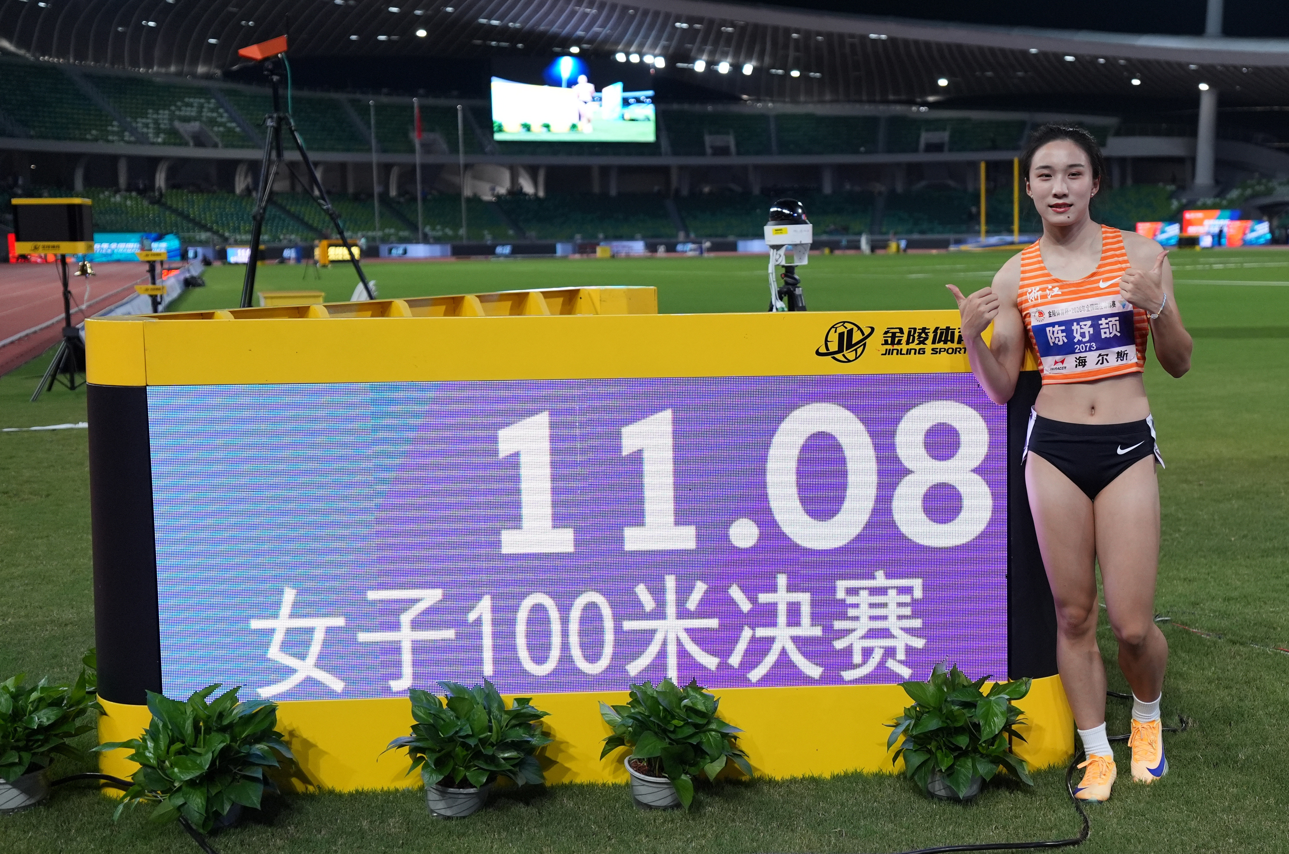 8月13日,浙江体彩队选手陈妤颉在女子100米决赛后和成绩显示屏合影。她以11秒08的成绩获得冠军。新华社记者 贾宇辰 摄