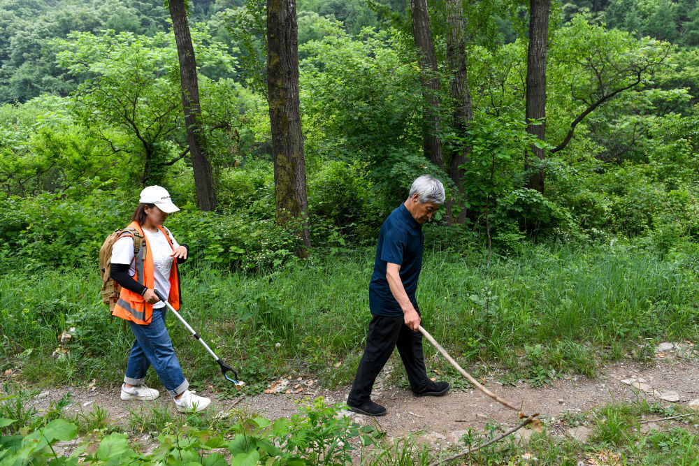 2024年5月23日，在北京市延庆区石峡村，身患听力残疾的长城保护员梅景田（右）和外甥女刘红岩在前往长城的山路上。上世纪80年代初，梅景田开始自发保护长城，已带动许多村民形成保护长城的意识。2025年他获得“全国自强模范”称号。