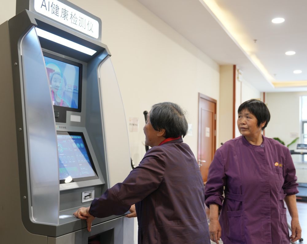 2025年4月8日，在江苏无锡滨湖区一养老院，一名老人（左）在工作人员的协助下使用AI健康检测仪。新华社记者 柳文惠 摄