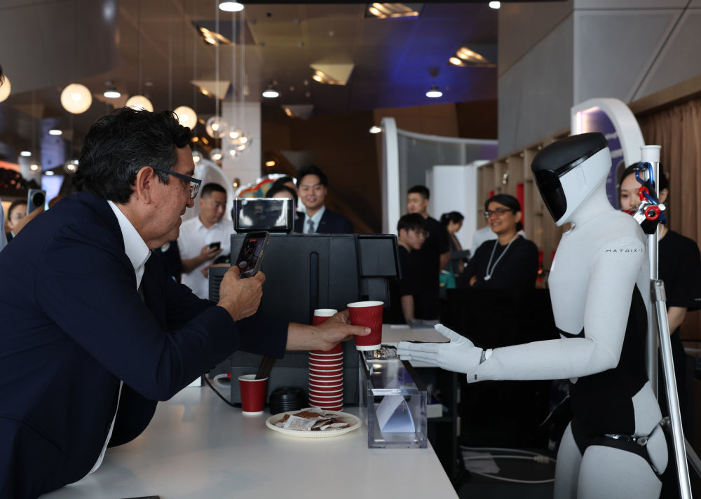 6月24日，在大连国际会议中心，嘉宾体验机器人制作咖啡。新华社记者 程婷婷 摄