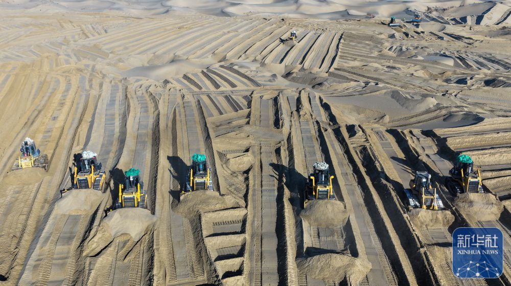 ↑ 在新疆和田地区墨玉县喀瓦克乡，大型机械在沙漠中穿梭作业、平整沙地（1月11日摄，无人机照片）。