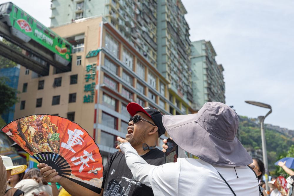 ↑ 4月23日，在重庆市渝中区李子坝观景平台，外籍游客摆出“吃”轻轨的姿势拍照。