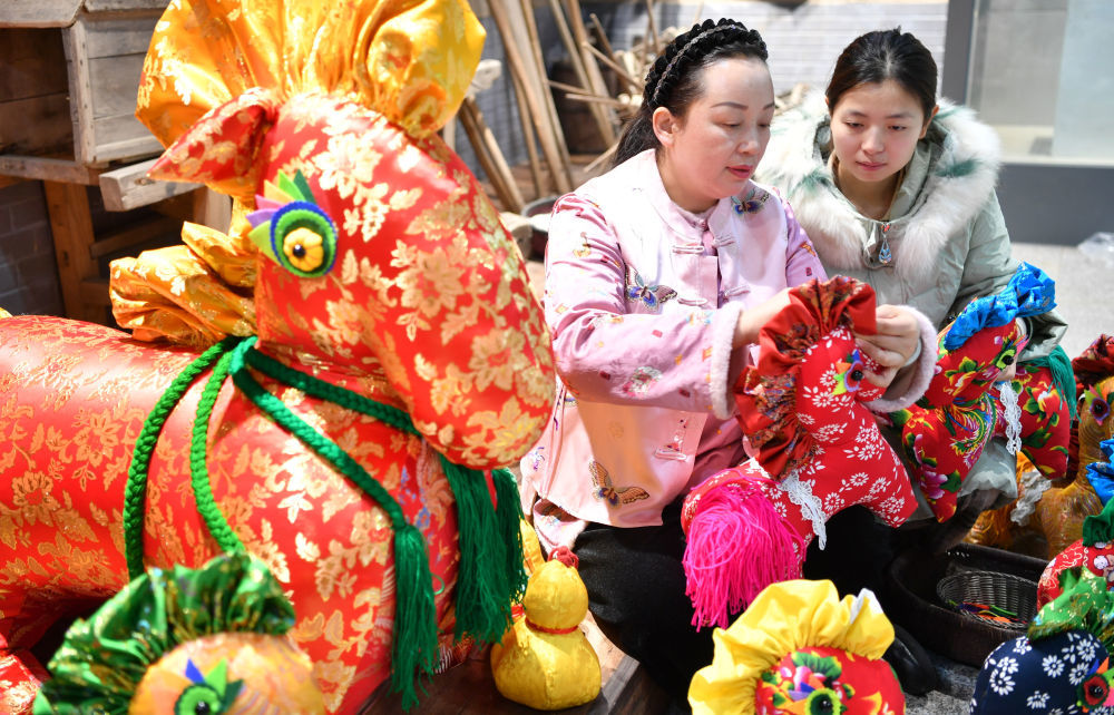 1月22日，河南驻马店市非遗香包制作技艺传承人王彩红（左）赶制新春特色香包。新华社发（弓华静摄）