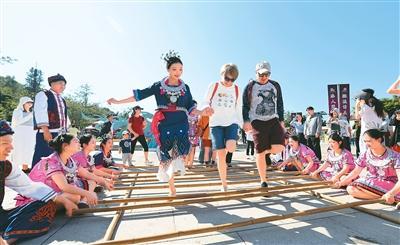 在三亚南山文化旅游区，景区演员和外国游客跳竹竿舞。陈文武摄（人民图片）