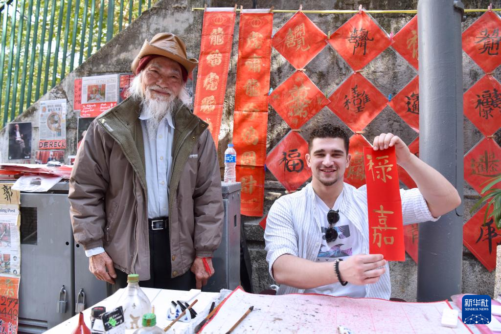 2月13日,在香港楼梯街,一名外国朋友展示郭腾龙(左)为其取的中文名字。新华社记者 陈铎 摄