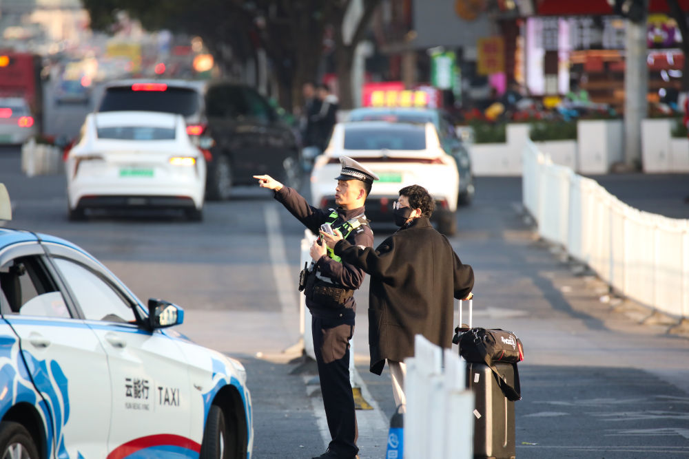 ↑ 2月16日，在云南省昆明市站前路，民警为刚出站的游客指路。新华社发（李云生摄）