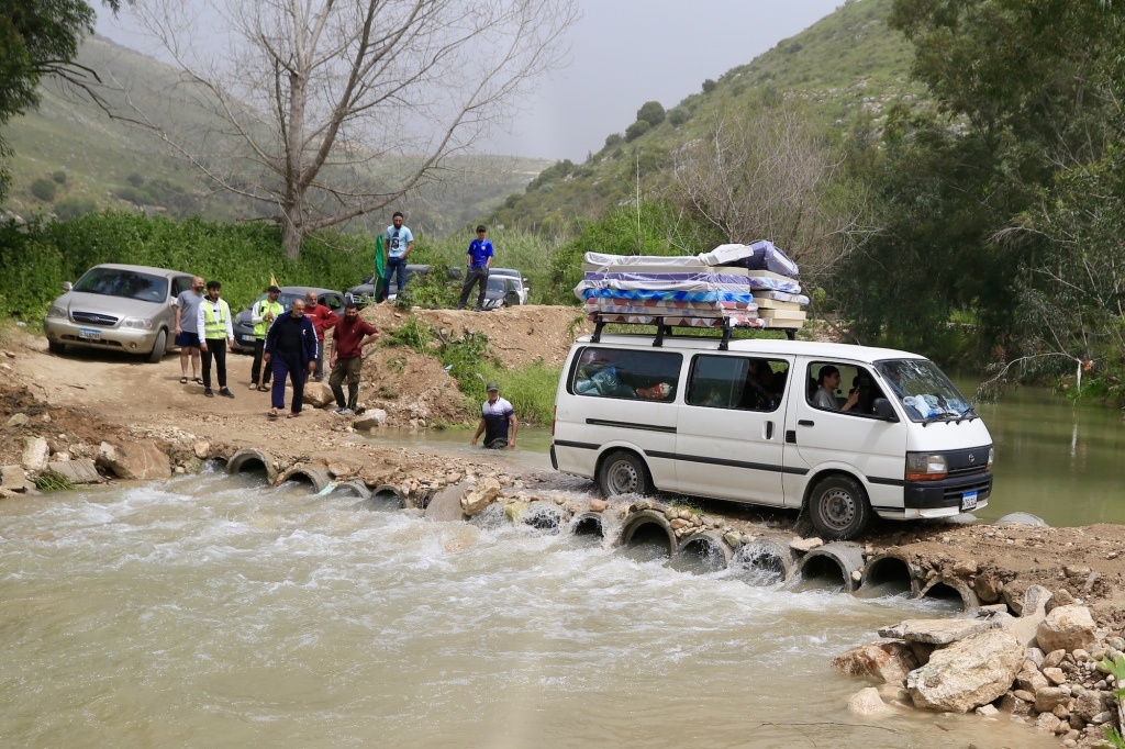 当地时间2026年4月18日，在黎巴嫩南部提尔附近的贝迪亚斯，返回家园的人们乘坐车辆经过利塔尼河上的一座临时桥梁。新华社 图