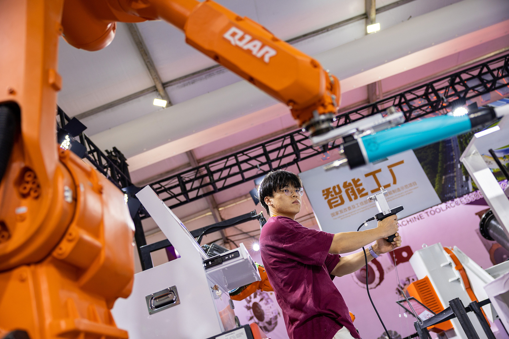 机床工具展览会现场，工作人员向客户展示机床设备