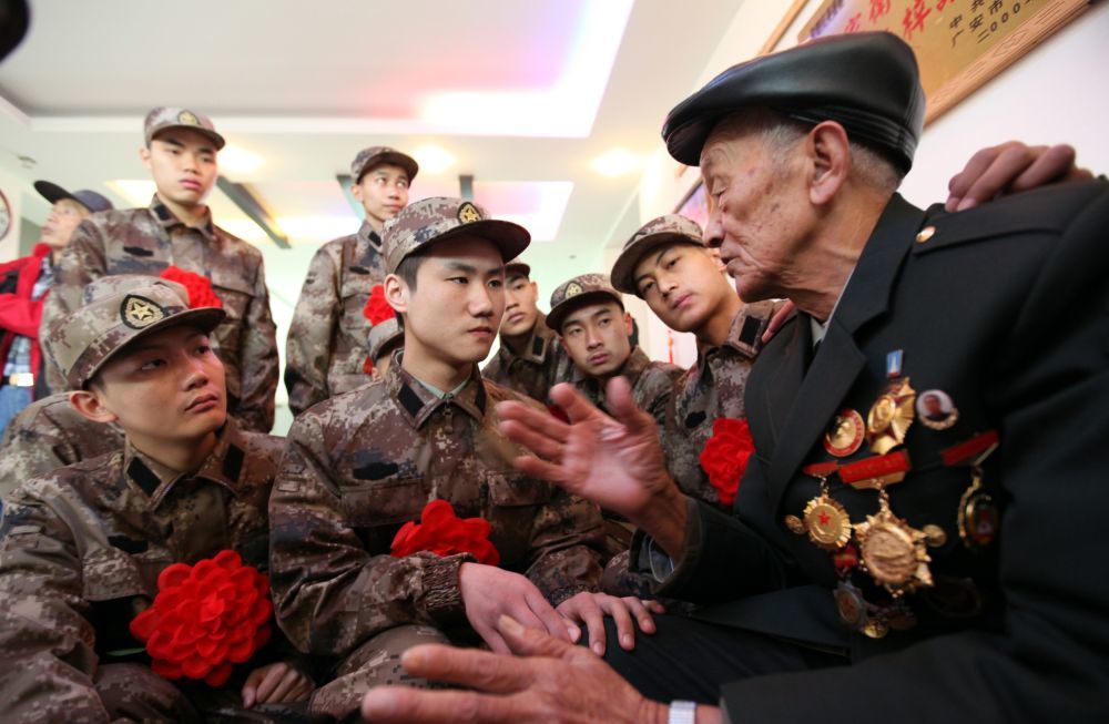 柴云振给来家中探望、即将启程奔赴军营的新兵们讲述战斗故事(资料照片)。新华社发