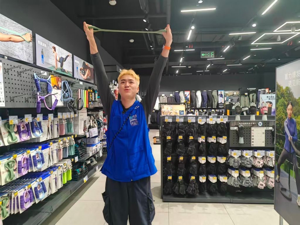 在迪卡侬成都世豪店,门店工作人员给消费者展示弹力带的用法。新华社发