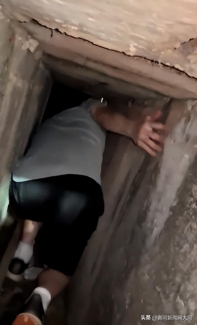 男生爬下下水口帮取手机。图/视频截图