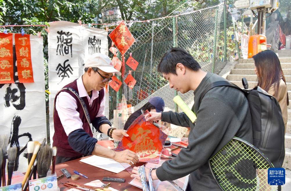 2月13日,在香港楼梯街,萧嘉豪(左一)在挥春档忙碌。新华社记者 陈铎 摄