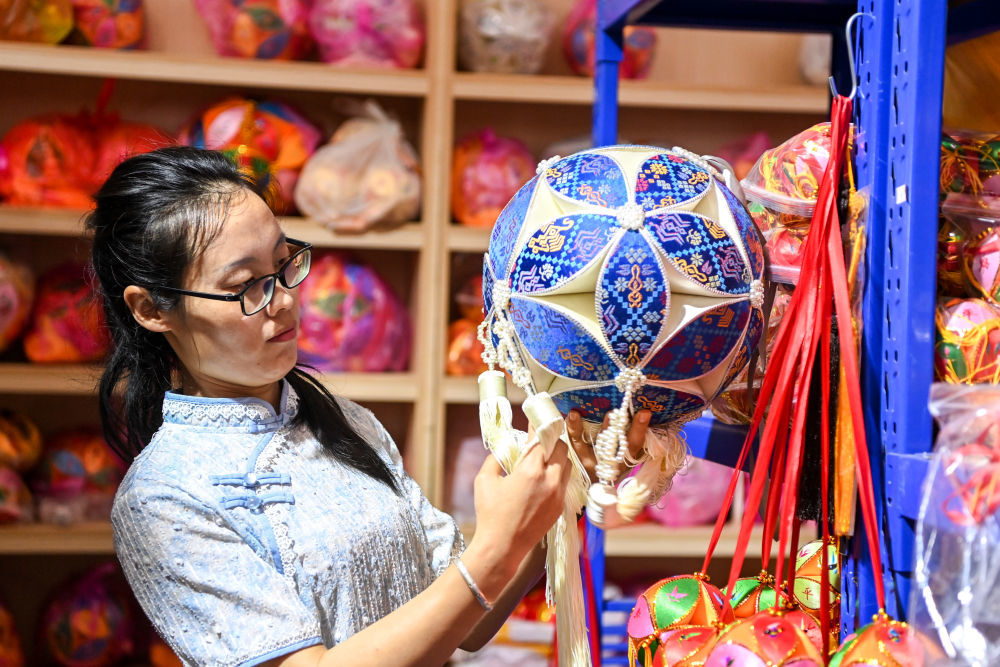 2024年4月3日，在广西靖西市的一家绣球生产企业，总工艺师王秀芬在检查绣球成品的质量。位于广西西南部的靖西市，有着悠久的绣球制作历史。如今，绣球这一文化符号与旅游产业深度融合，已经成为当地实现乡村振兴和经济转型的重要抓手。