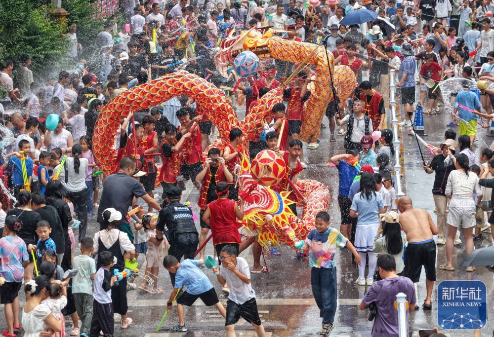 ↑ 6月20日,人们在贵州省黔东南苗族侗族自治州施秉县城参加“泼水龙”活动(无人机照片)。新华社发(磨桂宾摄)