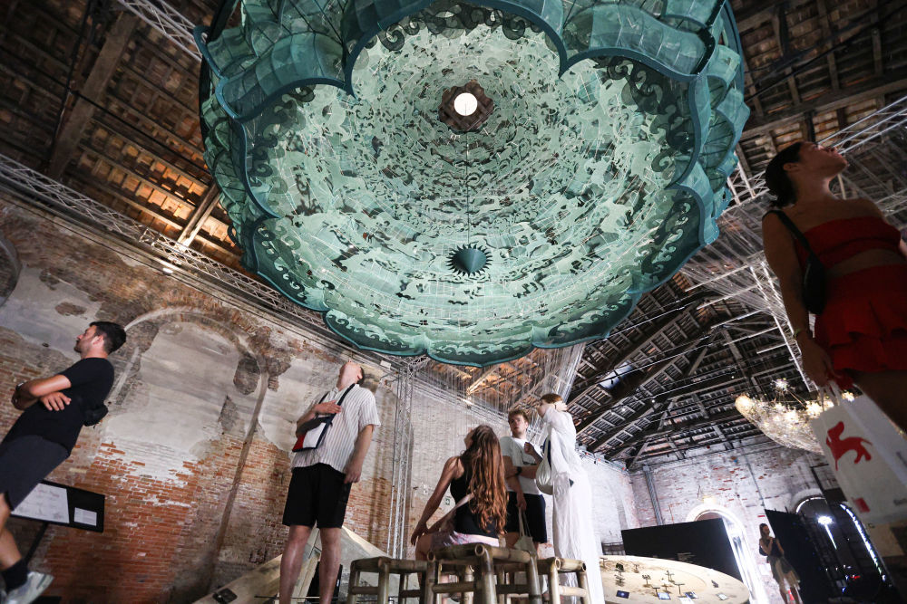 2025年7月16日，在意大利威尼斯，参观者在第19届威尼斯国际建筑双年展中国馆观看展品《苍穹》。本届中国馆展览以良渚文明、敦煌石窟、北京中轴线、城市交通与未来城市为主题，展现中国建筑在传统与未来之间的对话与思考。