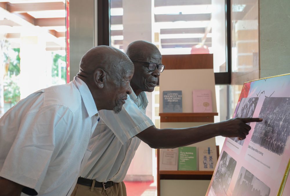 1月28日，在津巴布韦首都哈拉雷的中国大使馆，两名曾在中国接受培训的津巴布韦老战士在展板老照片上寻找自己。当日，大使馆举行向津巴布韦解放斗争老战士转交习近平主席复信活动。新华社记者 杨光 摄
