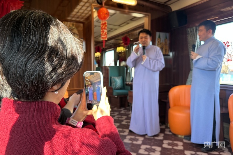 乘客在文旅专列上欣赏相声表演（央广网记者 周思杨 摄）